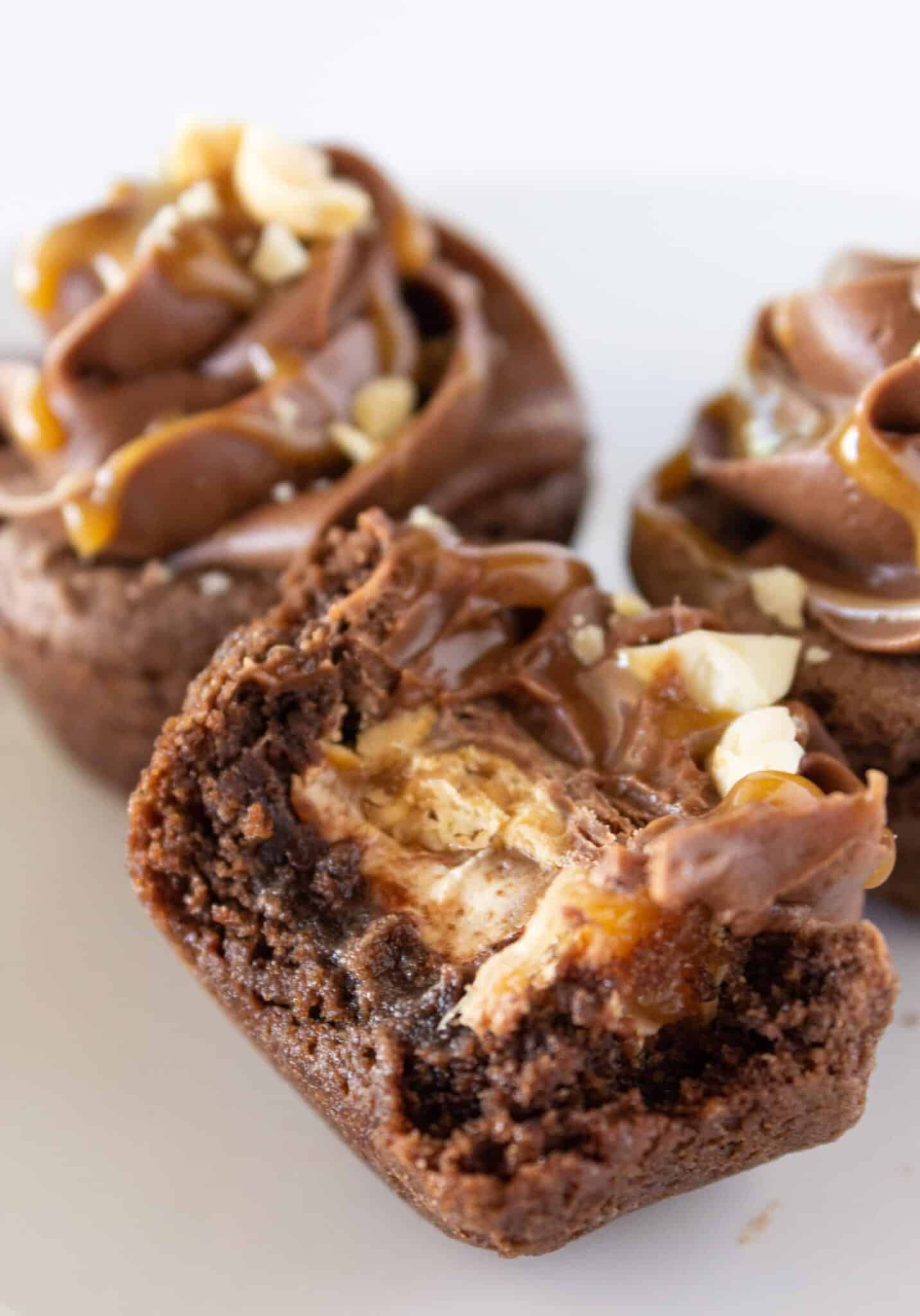 Easy Snickers Cookie Cups with a bite taken from one and you can see the candy inside.