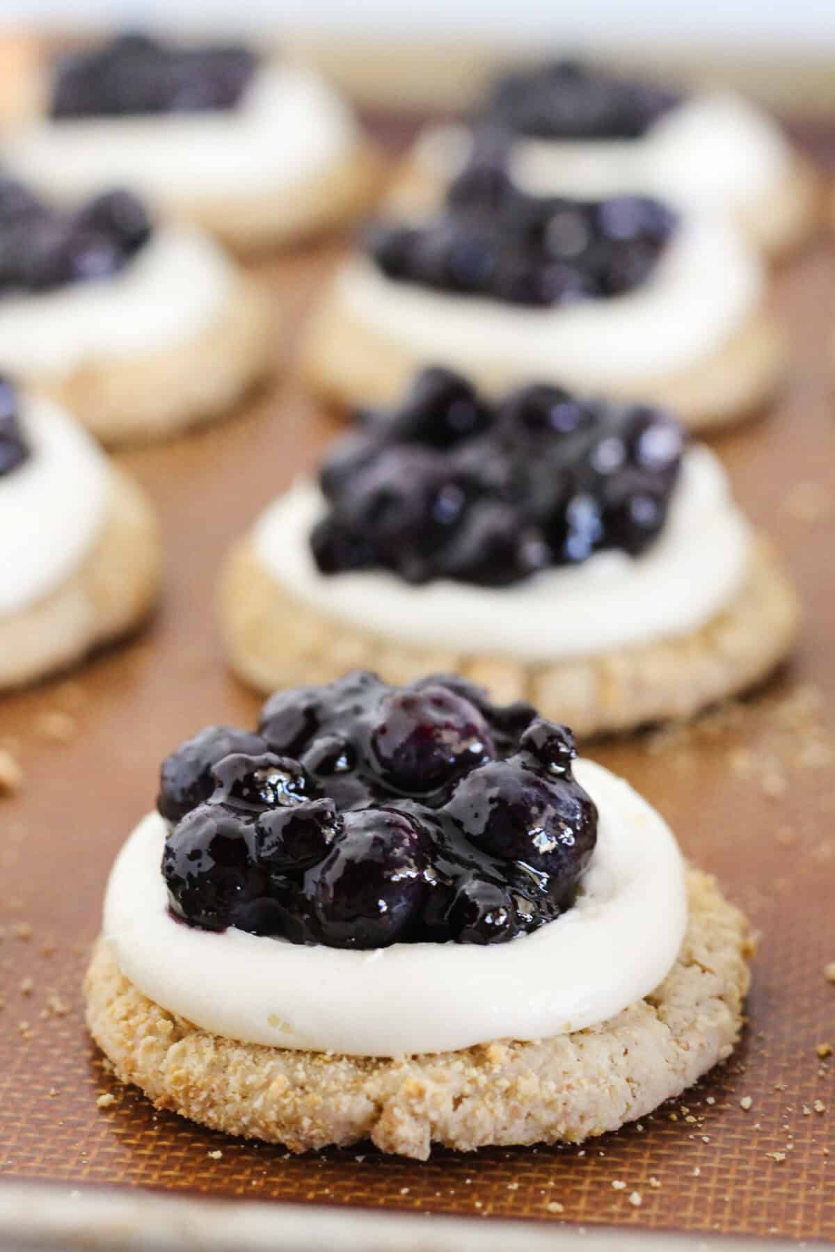 Blueberry cheesecake cookies with frosting and topping.