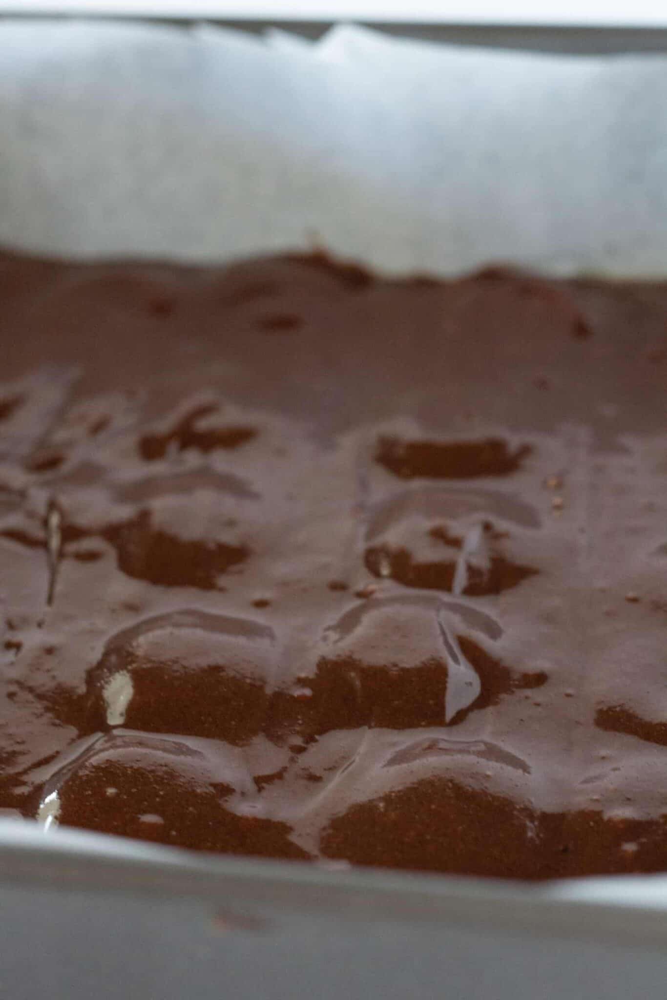 Adding cookies to brownie batter in pan and adding remaining batter to the top.