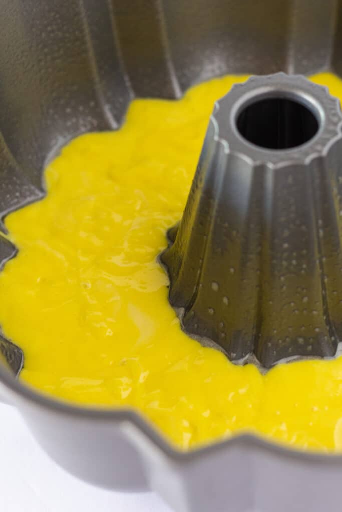 The first layer of yellow cake batter in the bundt pan.