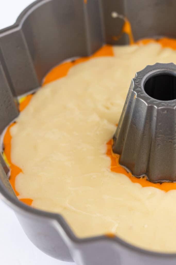 White cake batter poured on top of the other layers in the bundt pan.