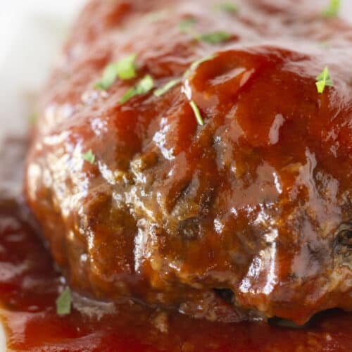 A whole meatloaf that was made in the crockpot with a sauce on top.
