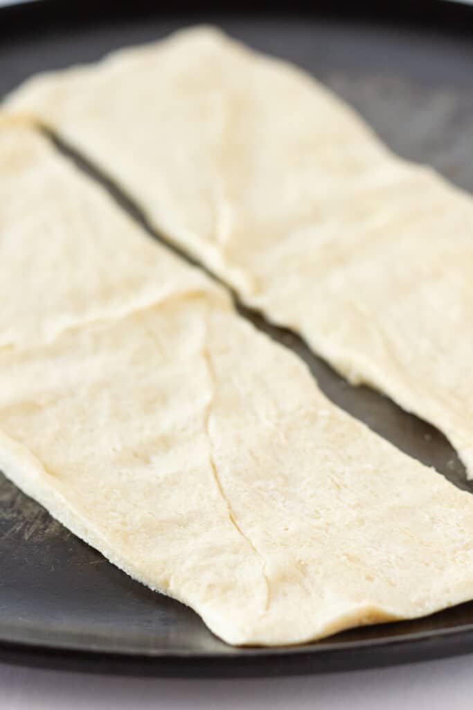 Crescent roll dough unrolled on a cutting board.