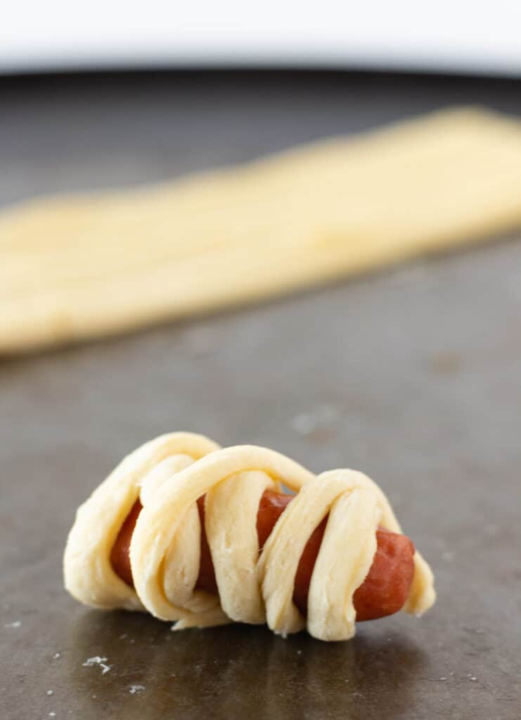 The miniature hot dog wrapped with another strip of crescent roll dough to create the Halloween mummies.