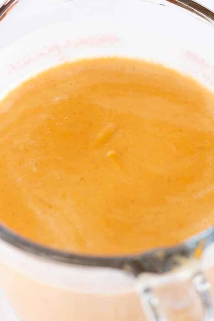 A glass measuring cup with pumpkin puree, pumpkin spice, milk, and buttermilk.