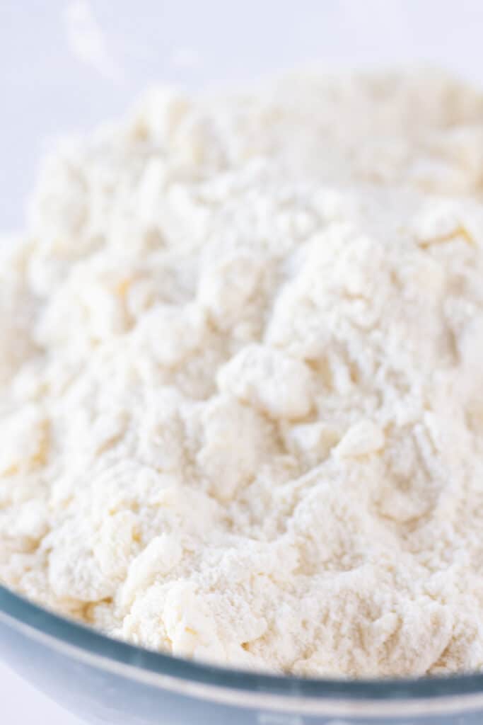 Cold butter and cake mix in a mixing bowl for topping the pecan cobbler.