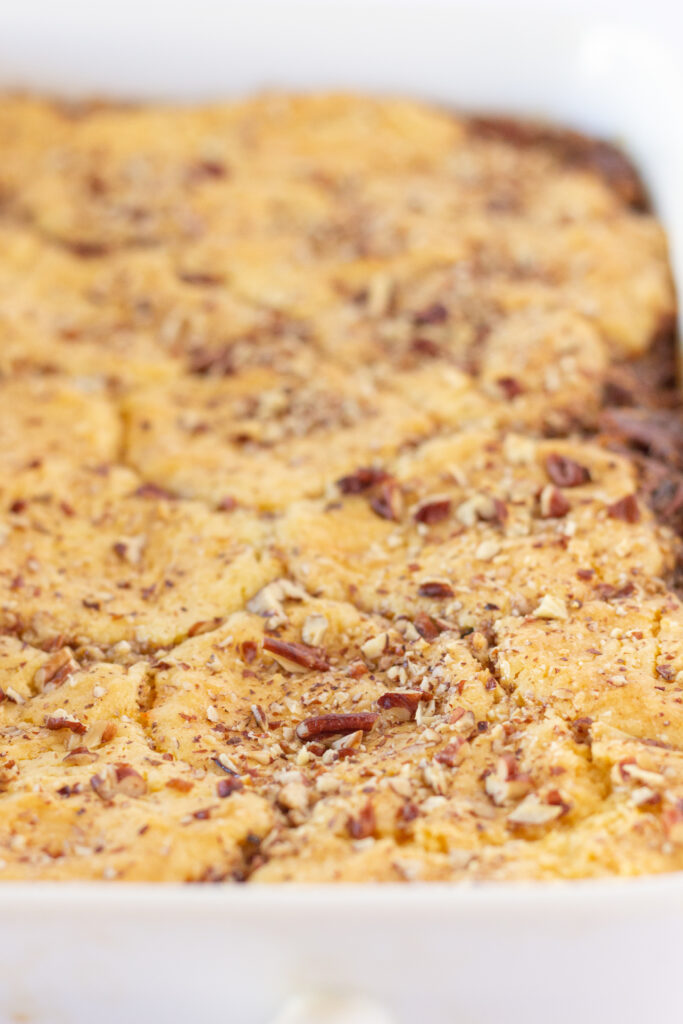 Pecan pie cobbler in a white bakign dish.