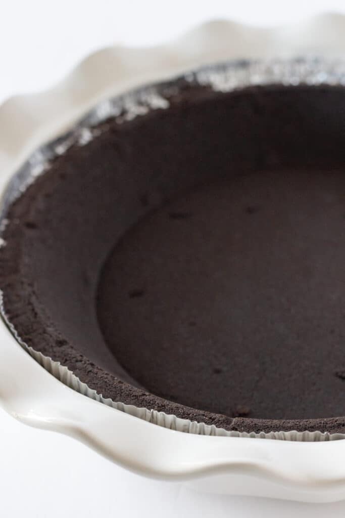 A chocolate crust in a white pie dish.