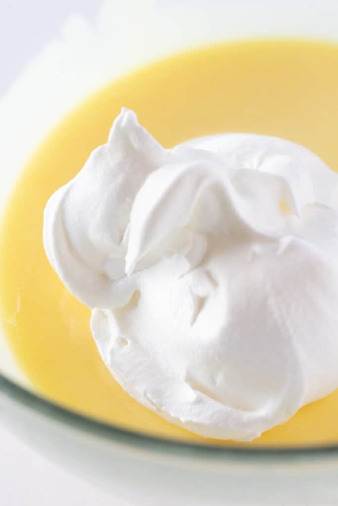 A glass mixing bowl with instant banana pudding and whipped topping.