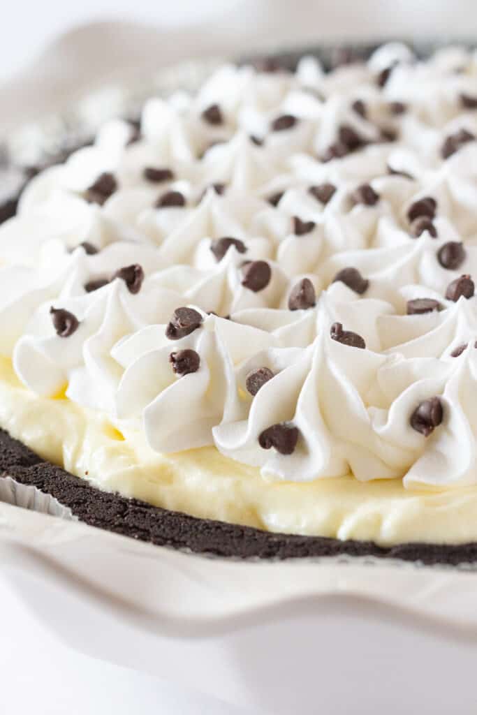 A chocolate banana pie topped with whipped cream and chocolate chips.