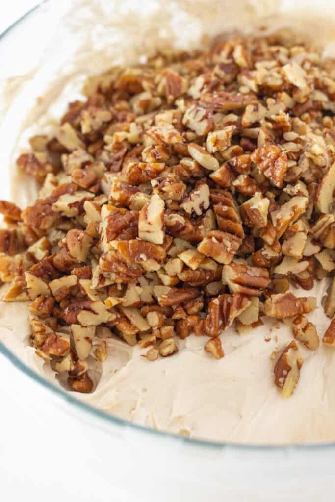 Pecan cream pie filling in a mixing bowl, topped with chopped pecans.