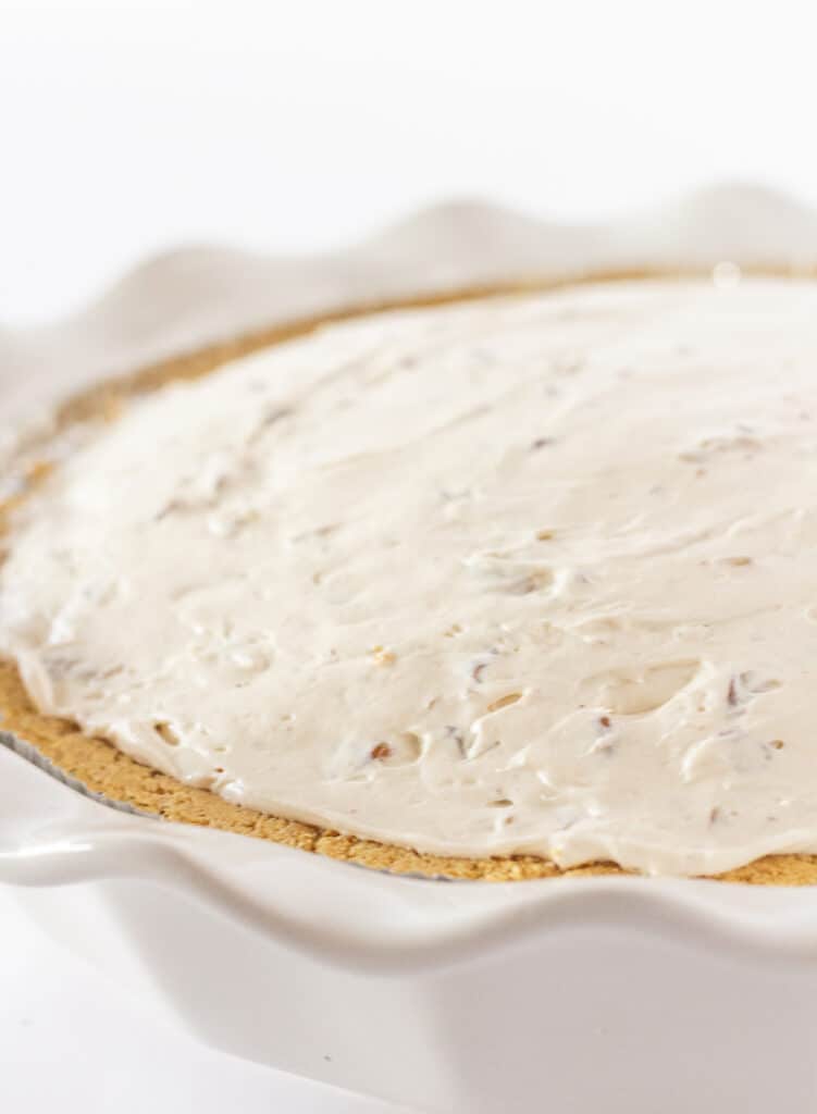 An undecorated pecan cream cheese pie in a white baking dish.