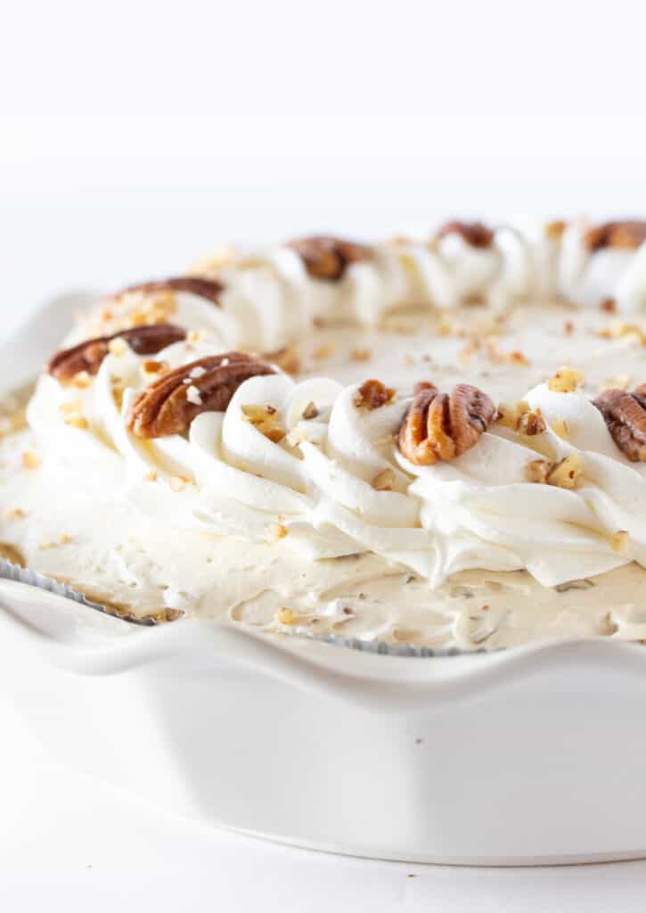 A pecan cream pie topped with whipped cream and whole pecans.