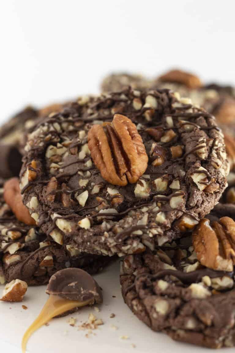 Turtle Cookies on a white cake plate with pecans and caramel.