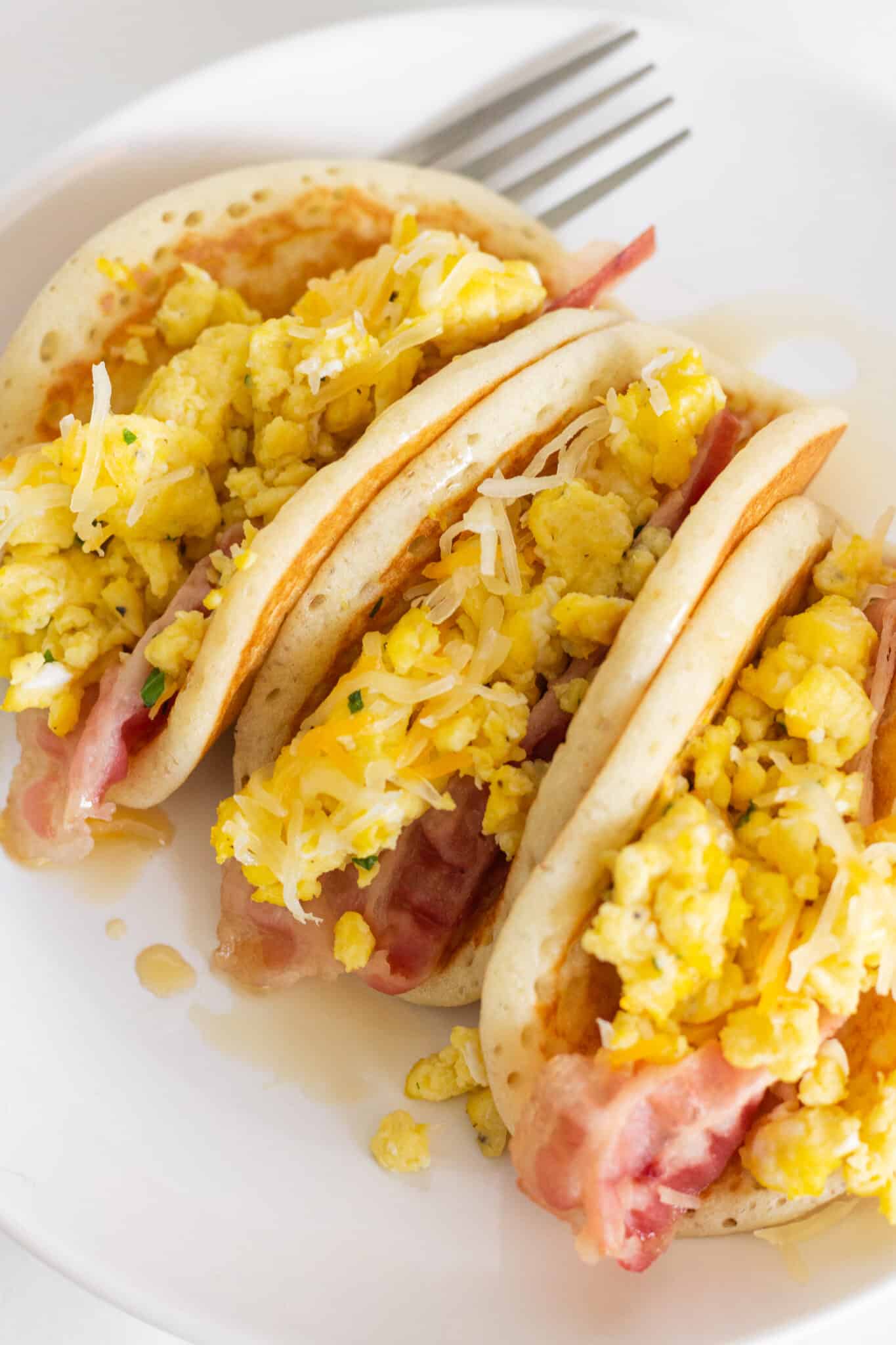 Looking at a plate with two pancake tacos with bacon and eggs.
