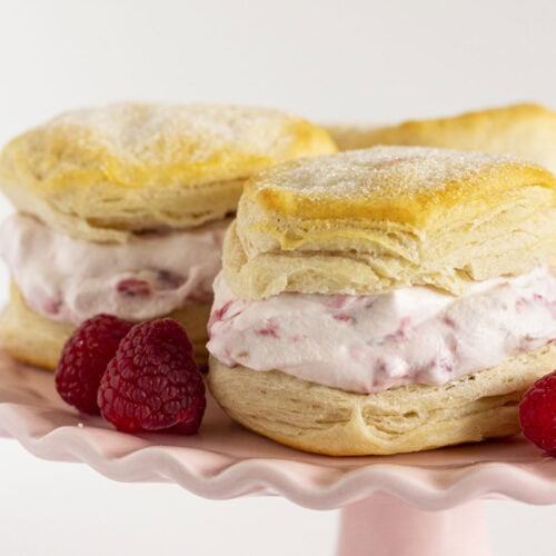 Raspberry shortcake on a pink cake plate with fresh raspberries.