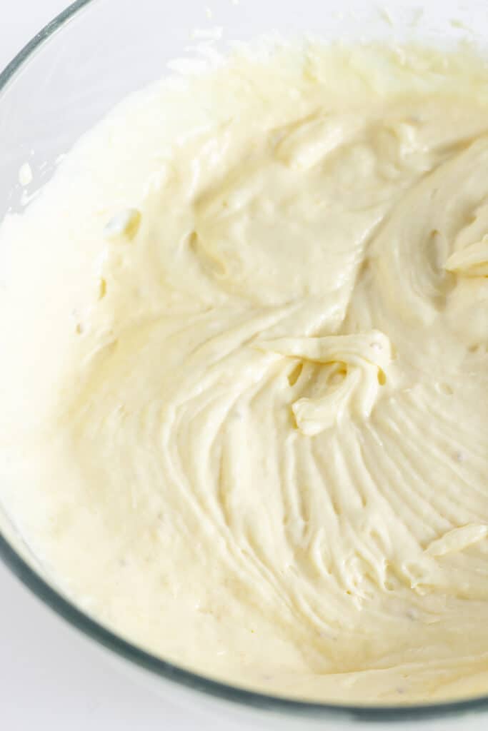 Cream cheese, whipped topping, and prepared banana pudding in a class mixing bowl.
