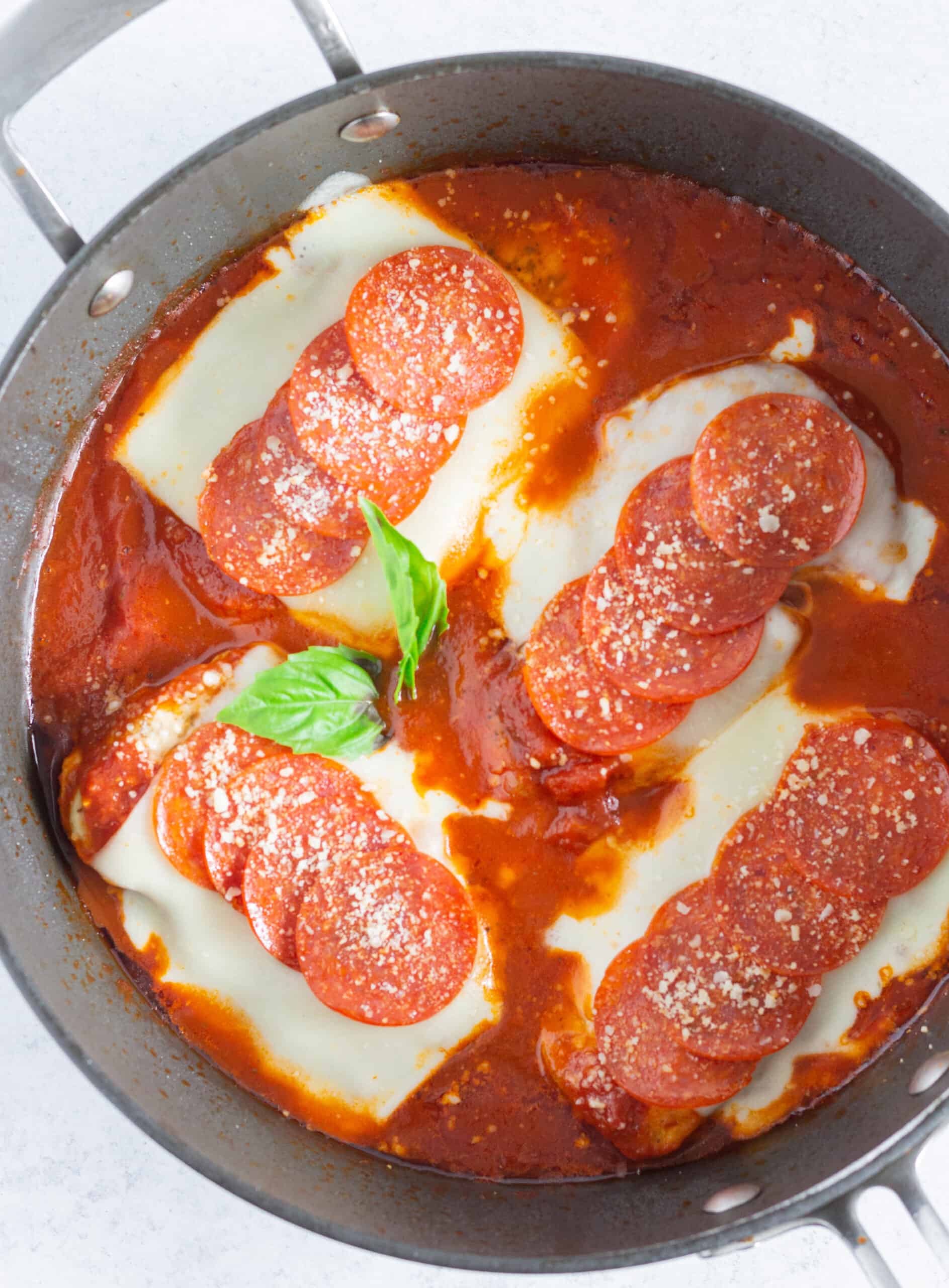 Looking down at a skillet of pepperoni pizza chicken.