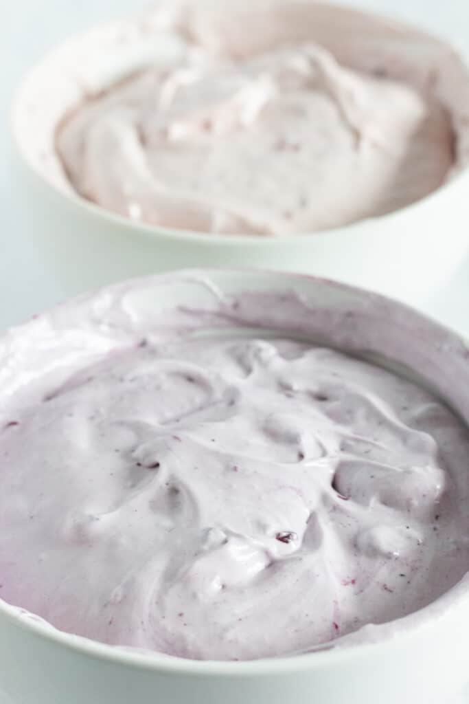 Berry cheesecake filling of various colors after having raspberry and blueberry jam stirred in.