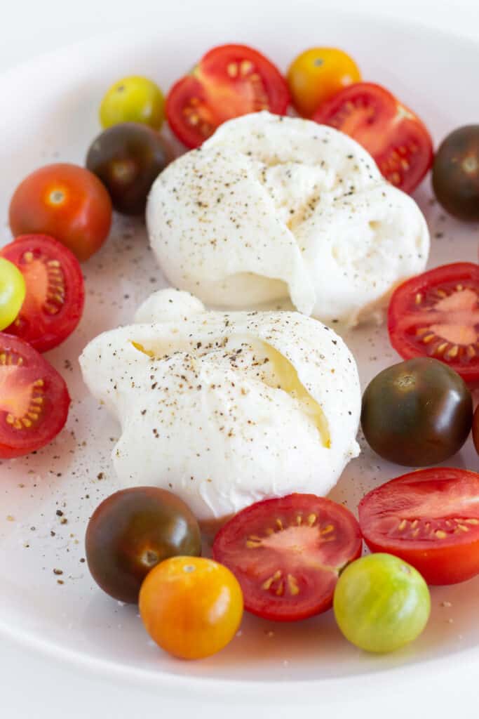 BUrrata, halved cherry tomatoes, and mini heirloom tomatoes on a platter.
