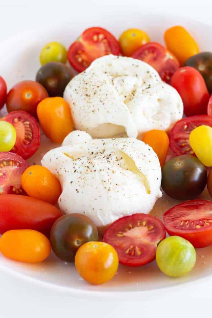 Burrata surrounded by tomatoes of various colors and sizes.