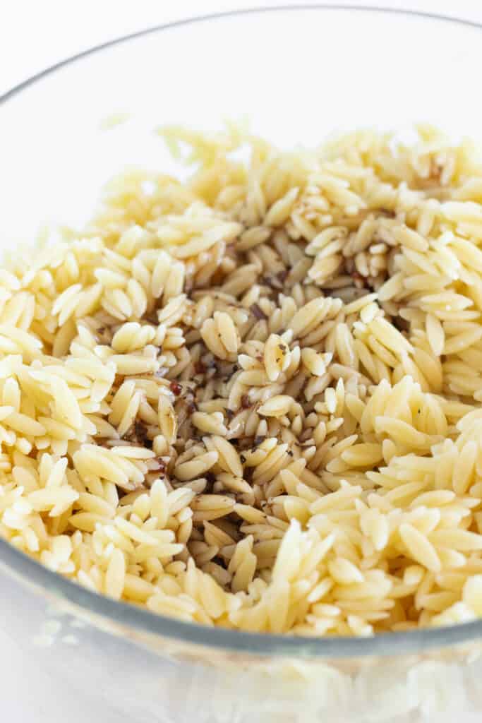 Orzo with vinaigrette in a glass mixing bowl.