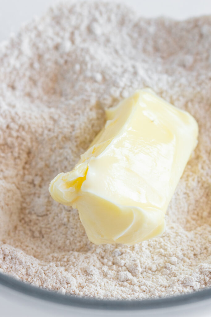 Softened butter with dry ingredients in a mixing bowl.