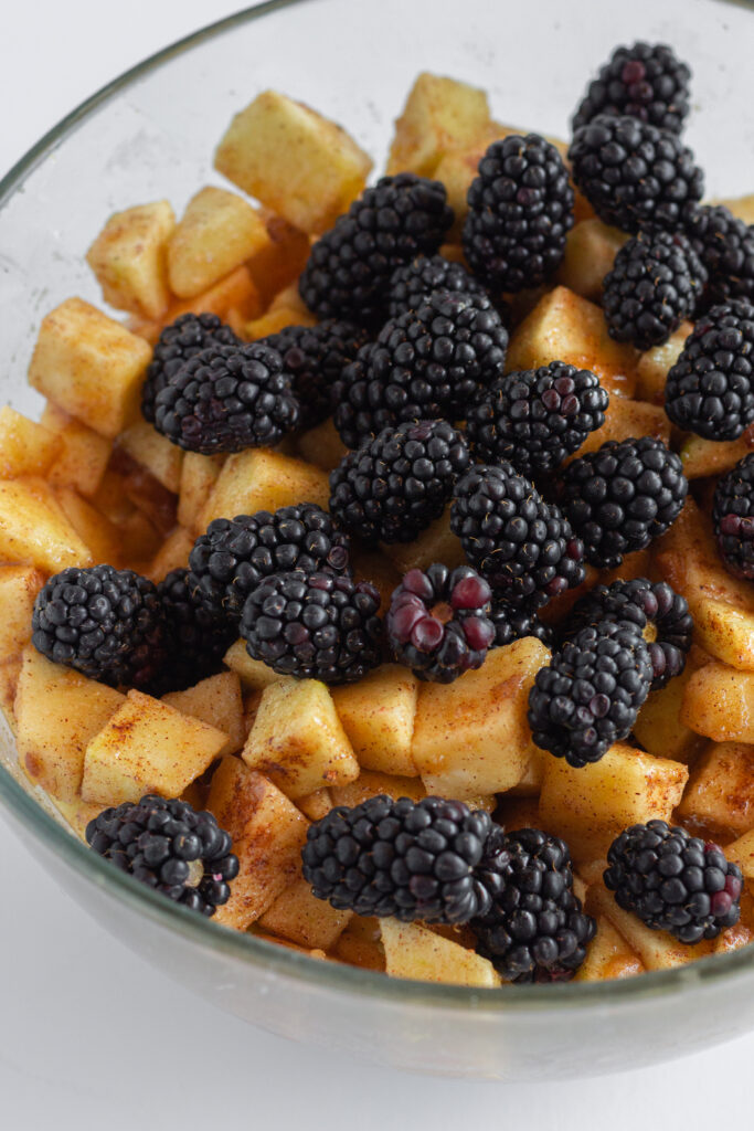 Cinnamon apples and blackberries in a glass mixing bowl.