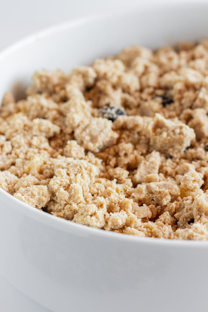 An unbaked apple blackberry crumble in a white mixing bowl.