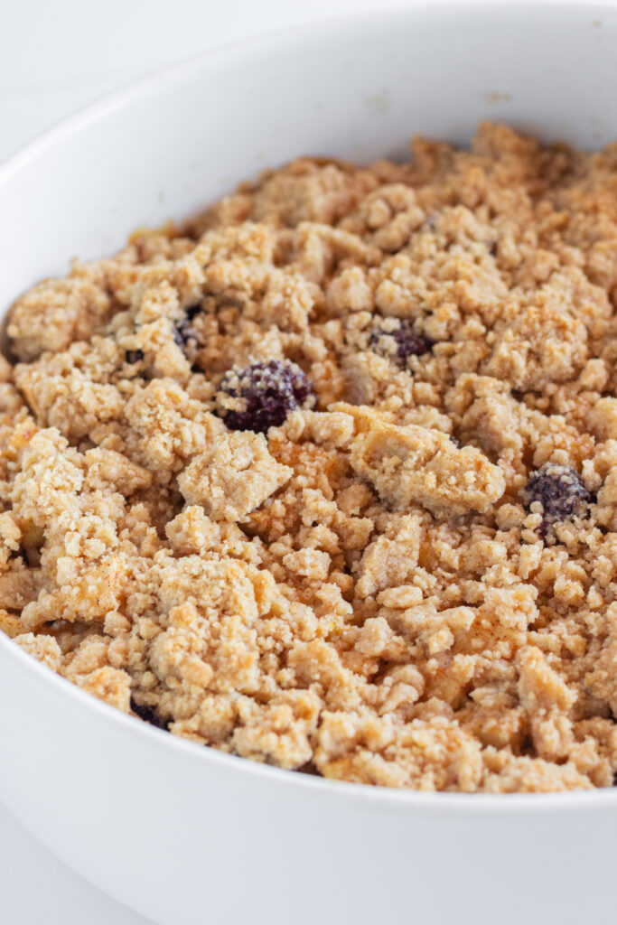 A baked blackberry apple crumble in a white mixing bowl.