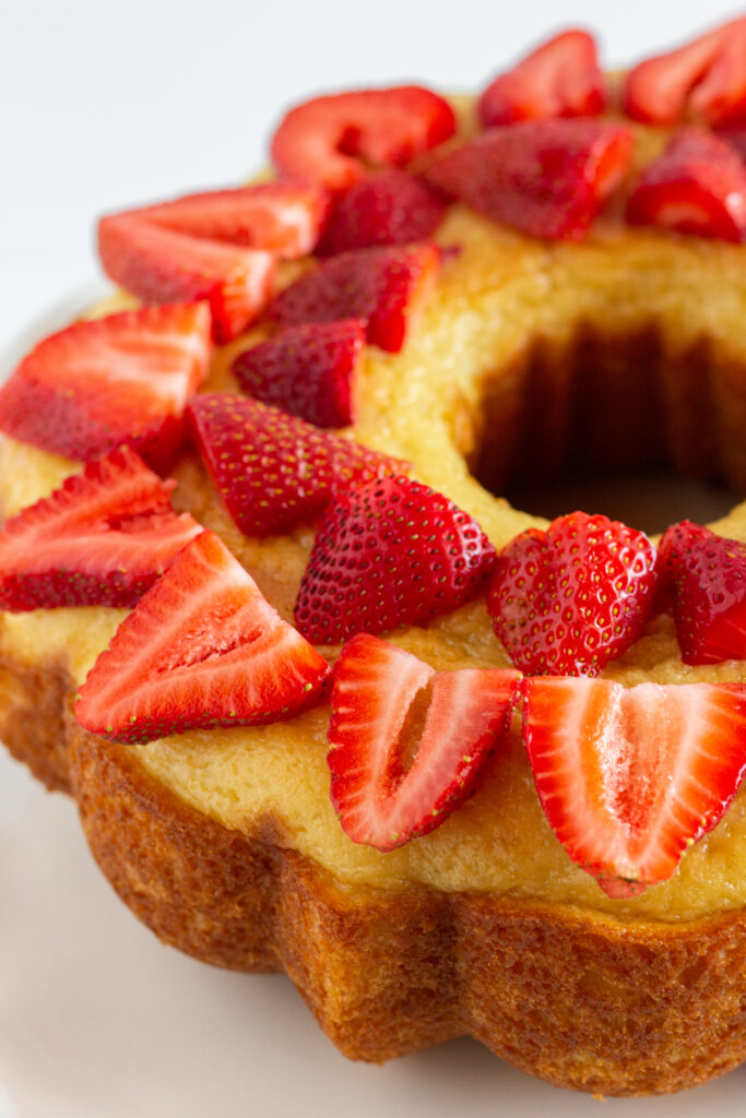 An inverted vanilla pound cake topped with fresh stawberry slices.