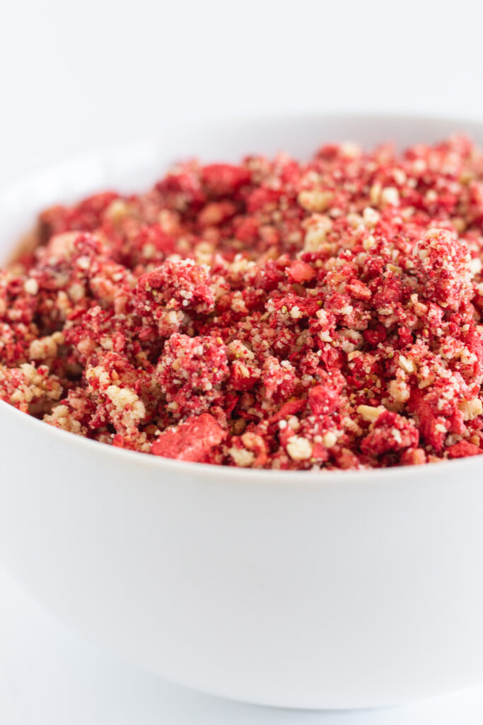 A white bowl of strawberry crunch topping.