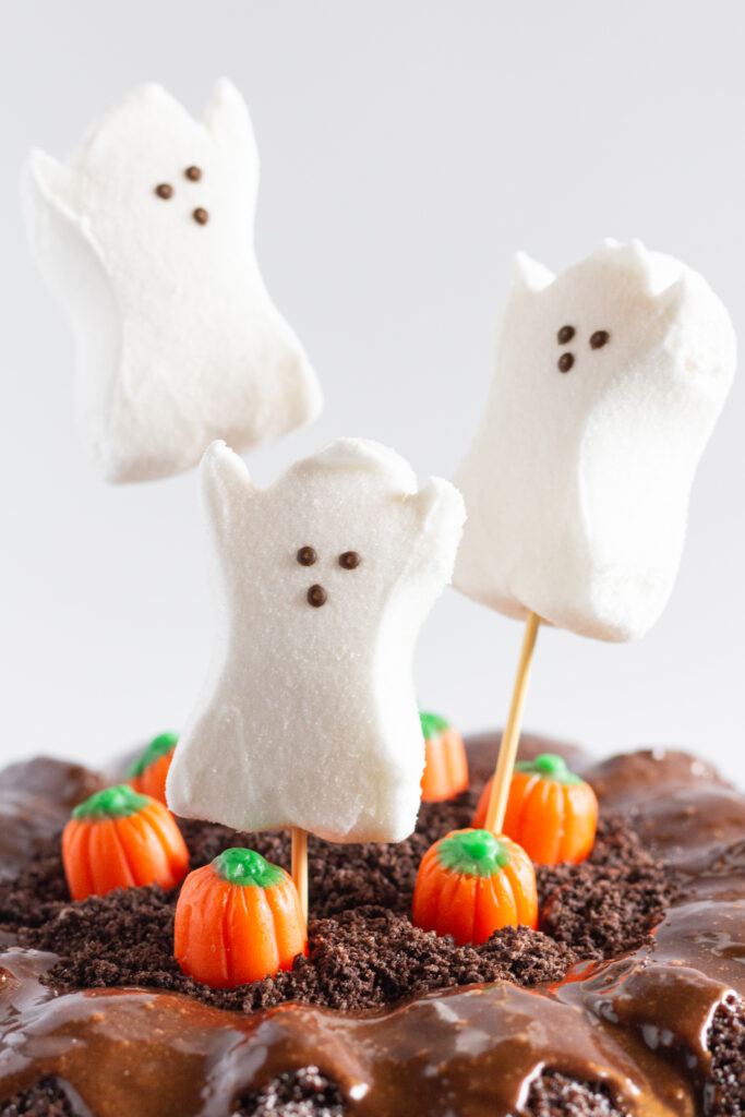 Close up photo of the top of the Halloween Bundt Cake showing the ghost peeps on skewers sticking into the top of the cake.