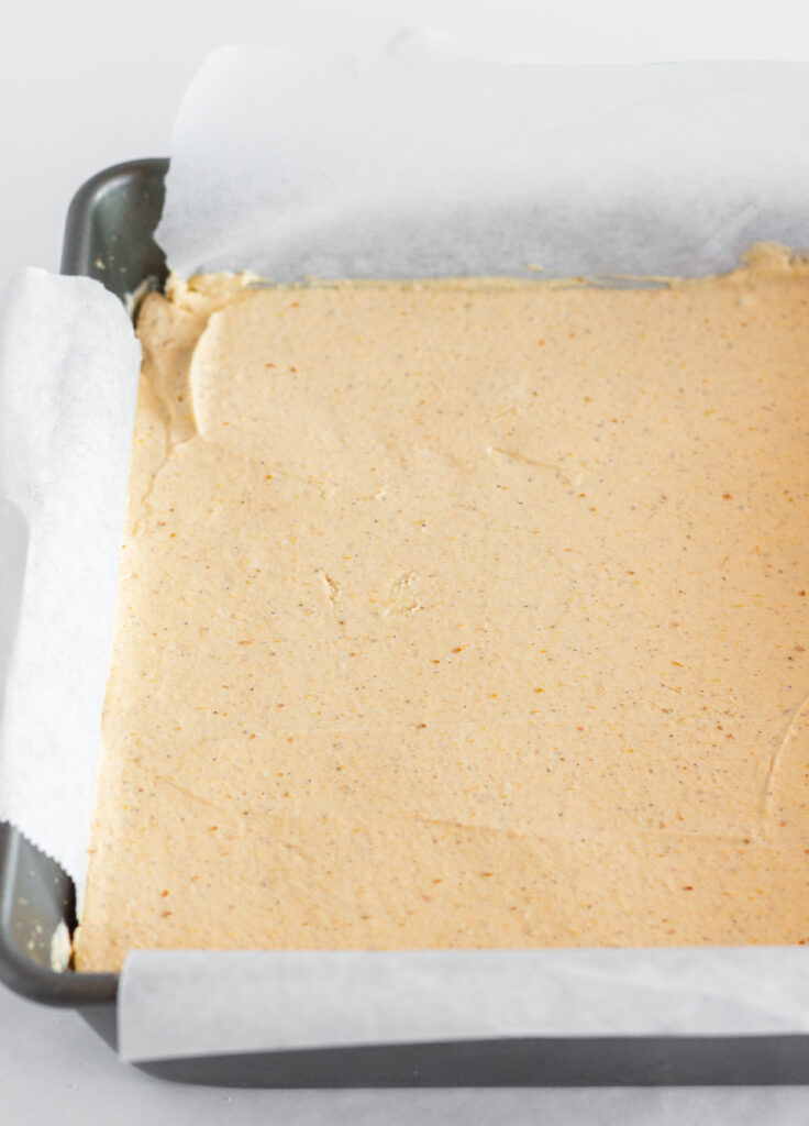The pumpkin cheesecake bars in a parchment lined baking pan before topping or slicing.