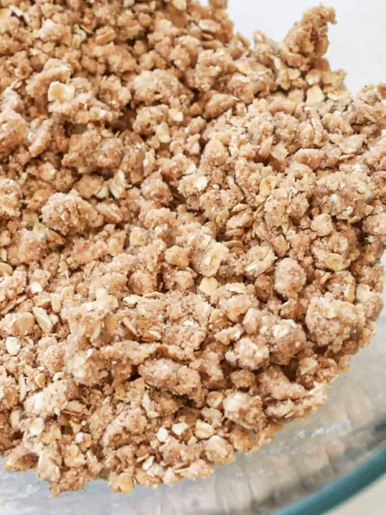 Oat topping for a cast iron apple crisp in a glass mixing bowl.