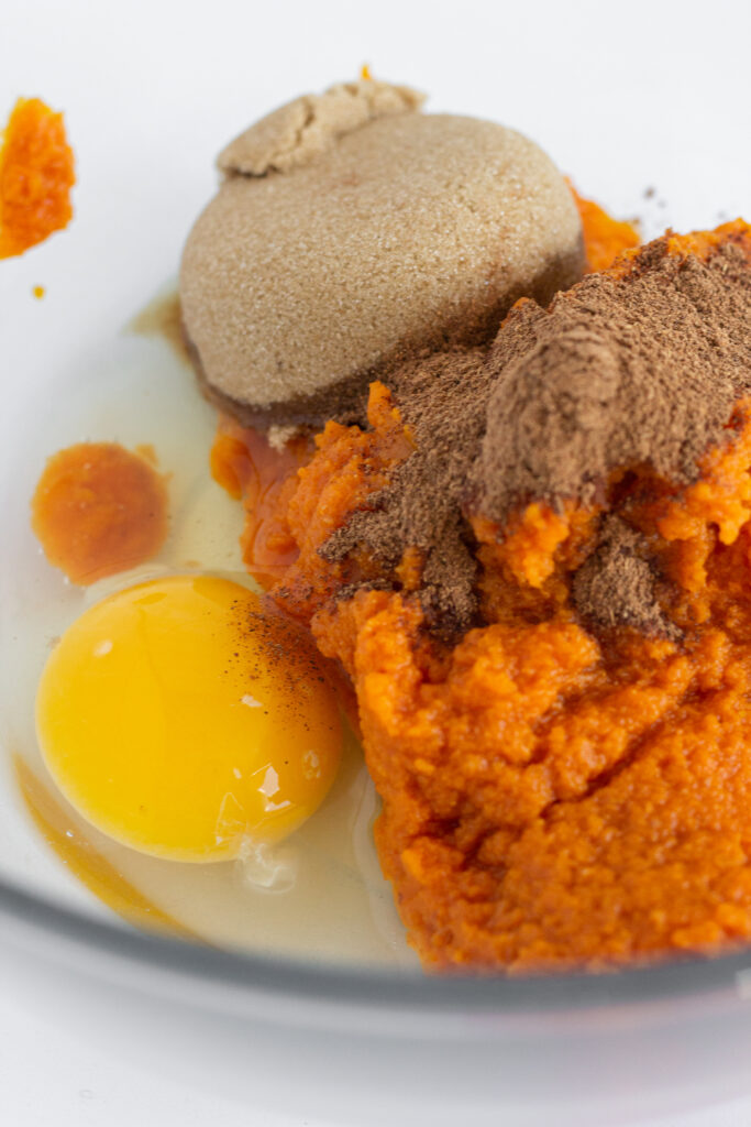 Pumpkin pie filling ingredients in a glass mixing bowl.