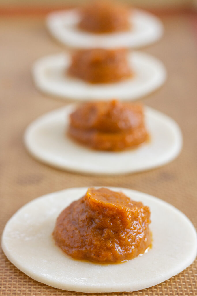 rounds of pie crust dough topped with pumpkin pie filling,