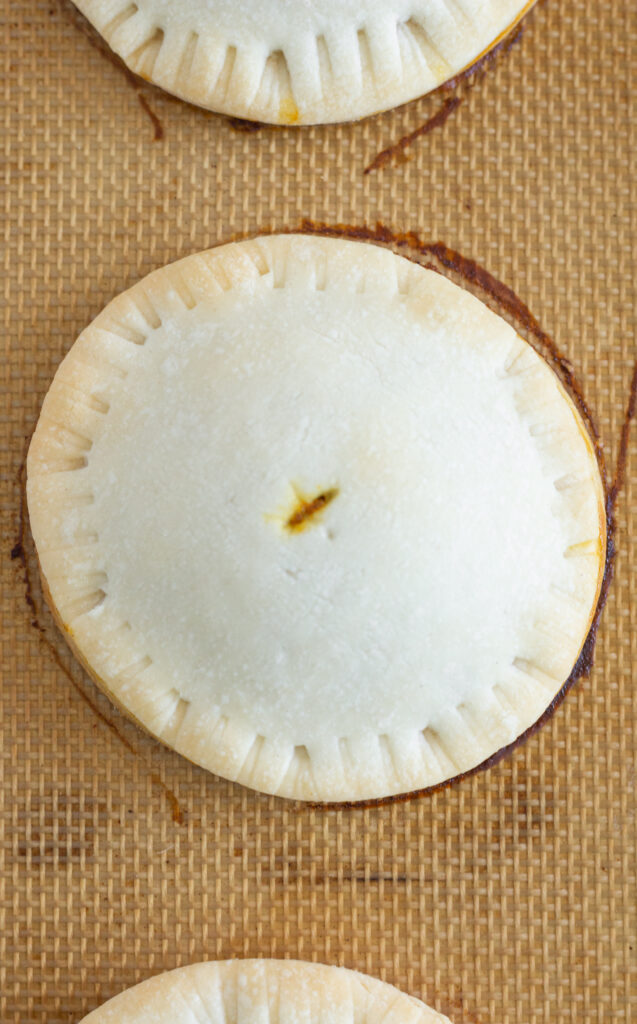 Baked pumpkin pie hand pies on a baking sheet.