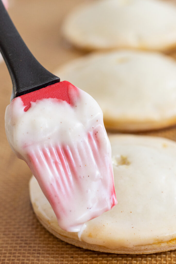 A silicone brush brushing glaze onto pumpkin handpies.