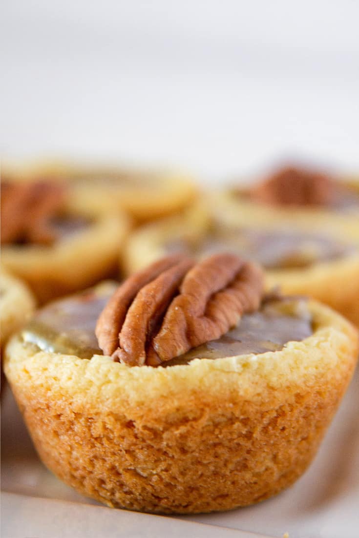 A plate of Pecan Pie Cookie Cups with a whole pecan half on top.