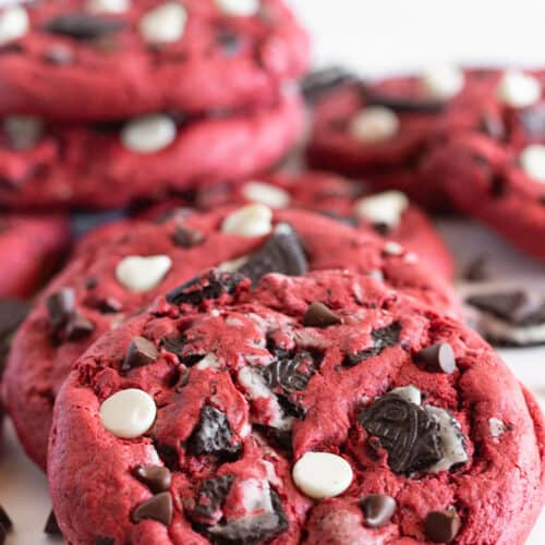 Red Velvet Oreo Cookies filled with Oreo cookie chunks and chocolate chips are leaned on each other.