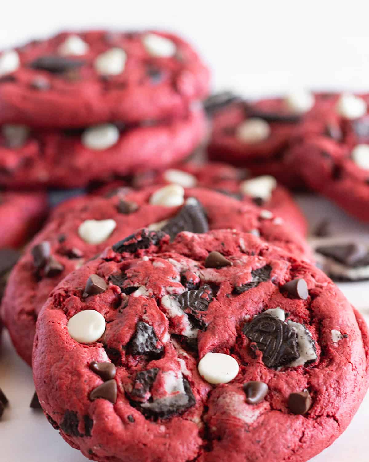 Red Velvet Oreo Cookies filled with Oreo cookie chunks and chocolate chips are leaned on each other.