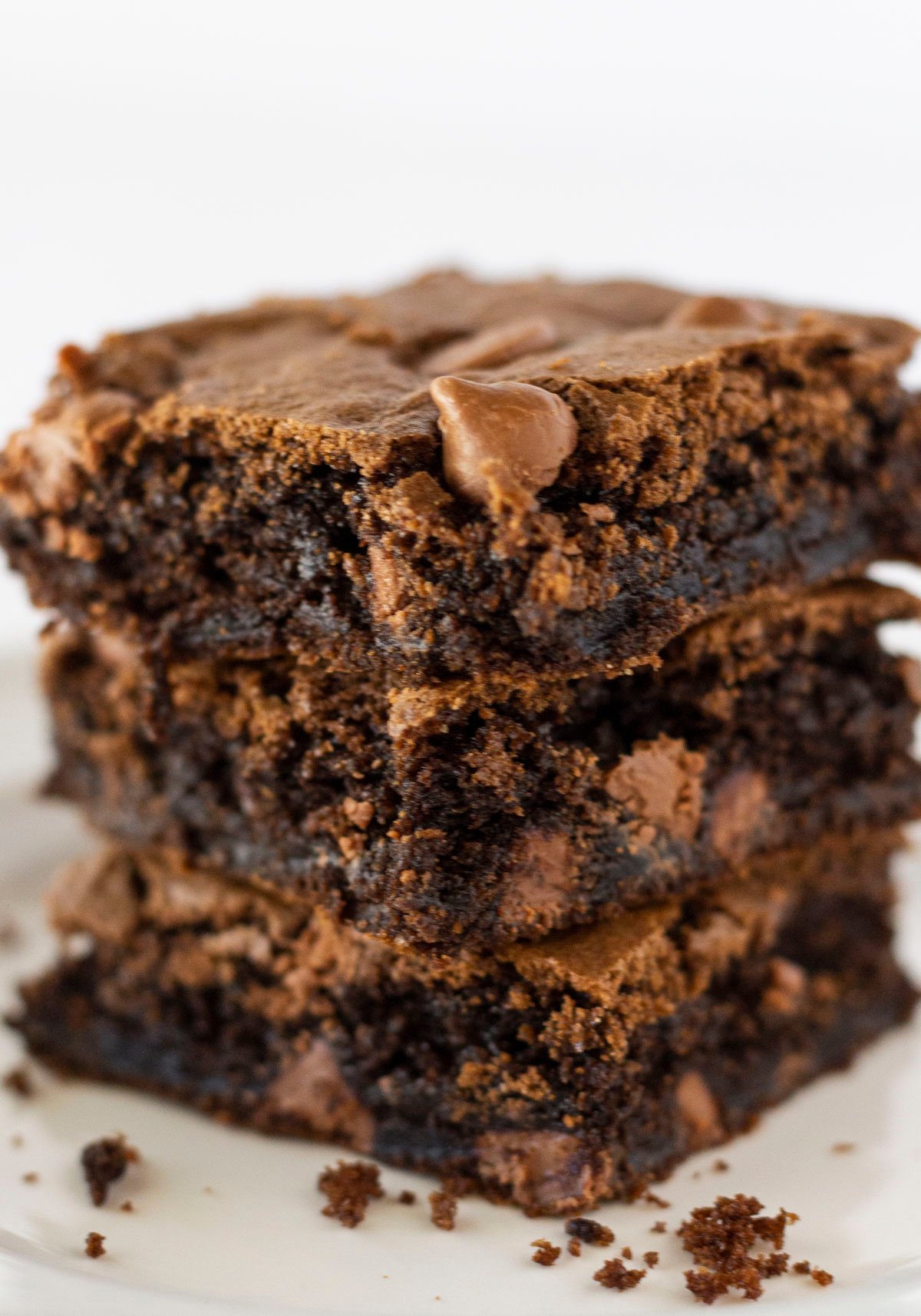 Stack of three Fudgy Cake Mix Brownies with a few chocolate crumbs around them.