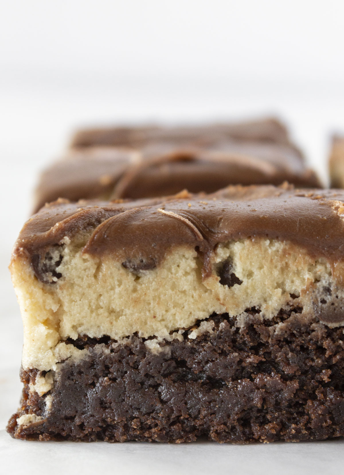 Cookie dough brownies in a line with one of them close up and being able to see all of the layers.