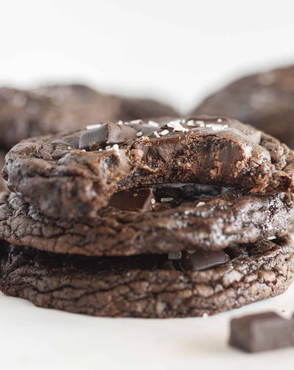 Three Dark Chocolate Cookies stacked on top of each other with a bite taken out of the one on top.