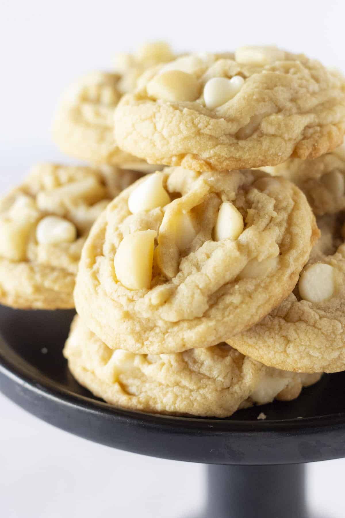 Soft Macadamia Nut cookies stacked on a black cake plate.