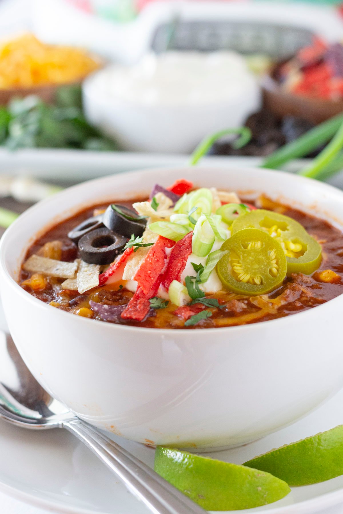 A bowl full of Taco Soup that was made in the crock pot with toppings in the background.