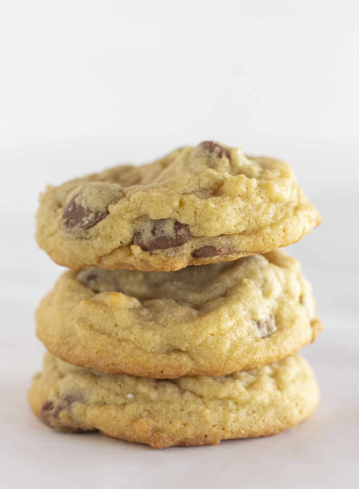 Three soft chocolate chip cookies stacked on top of each other.
