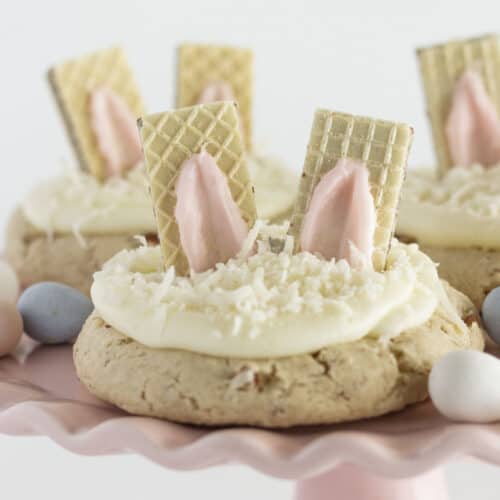 Three Bunny Cookies on a pink cake plate with candy eggs.