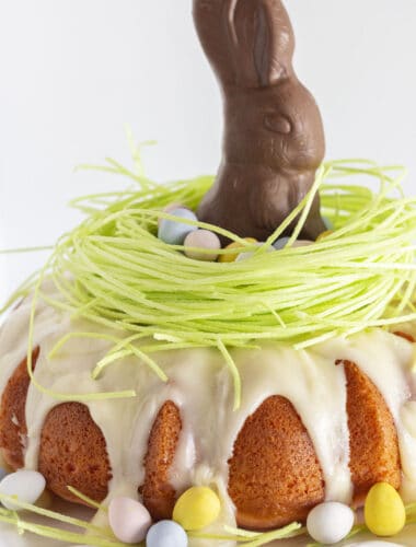 A pink velvet cake with edible grass and a chocolate bunny for Easter.